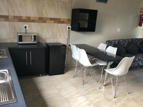 a kitchen with a black table and white chairs at Dam Vista Retreat in Giyani