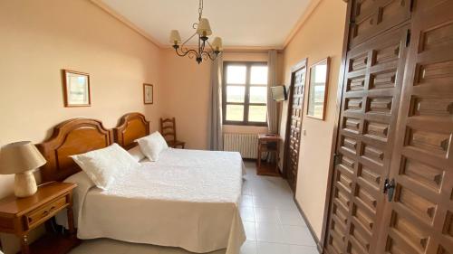 1 dormitorio con cama blanca y puerta en Hostal Las Paneras en Avila