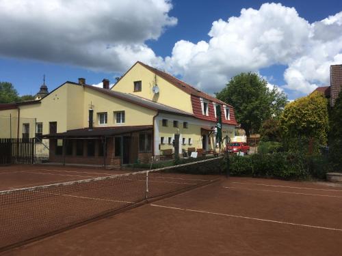 a tennis court in front of a building at Penzion u Příhodů in Jesenice