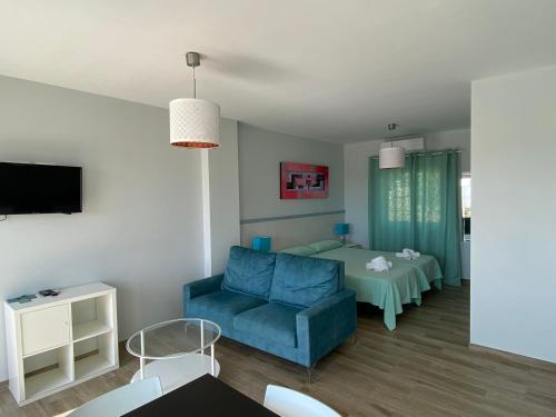 a living room with a blue couch and a bed at Mda Playa del Cantal in Mojácar