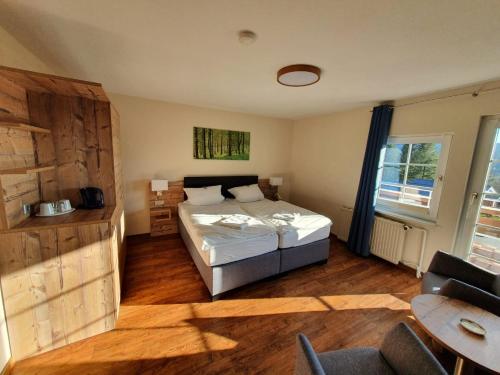 1 dormitorio con cama, mesa y ventana en Hotel Waldrausch, en Hahnenklee-Bockswiese