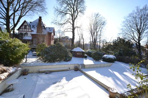 a yard covered in snow with a house in the background at Maison Montana in Brussels