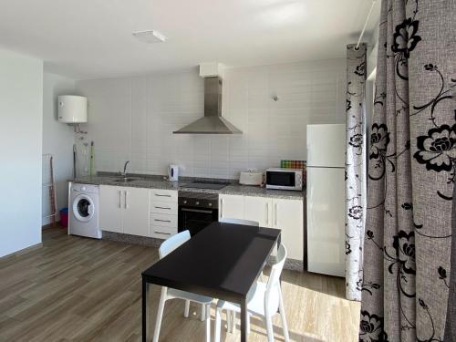 a kitchen with a black table and white appliances at Mda Playa del Cantal in Mojácar