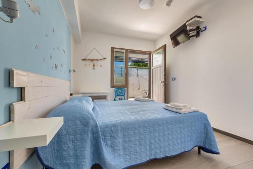 una camera con un letto blu e una finestra di Maresidence - il Residence sul mare a Torre Pali a Torre Pali