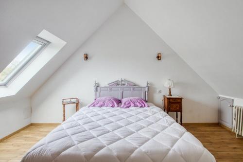 een slaapkamer met een groot wit bed met paarse kussens bij Maison de 3 chambres avec jardin amenage a Saint Marcouf in Saint-Marcouf