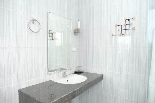 a white bathroom with a sink and a mirror at Joyful Hotel in Tanjungpandan