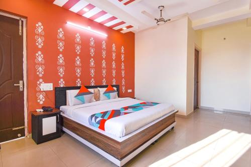 a bedroom with a bed with an orange wall at FabExpress Bzoie Heritage in Dehradun