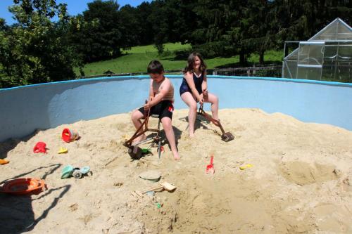 two children sitting in the sand in a swimming pool at Xavers Ranch in Meschede