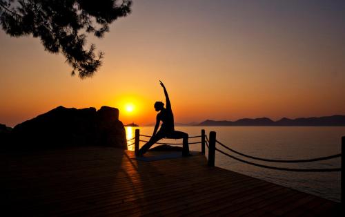 a woman sitting on a bench in front of the sunset at Perdue Hotel in Faralya