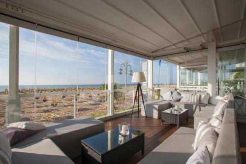 uma sala de estar com mobiliário branco e janelas grandes em Residence Atlantico em Lido di Jesolo