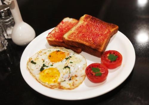 a plate with eggs and toast and tomatoes on a table at Hotel Planet Four in Lonavala