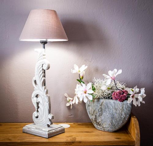 a lamp on a table next to a vase of flowers at Abacard Home Chambre d'Hôtes adult only in Roquemaure