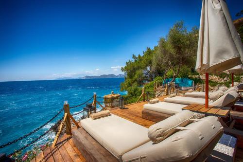 a row of beds on a wooden deck next to the ocean at Perdue Hotel in Faralya