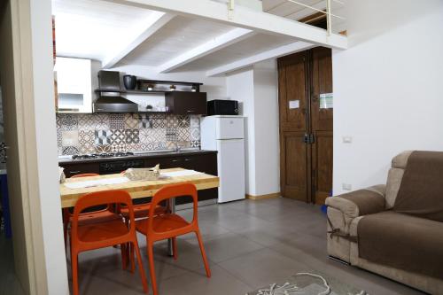 una piccola cucina con tavolo e due sedie arancioni di Appartamenti Laura Wi-fi a Curti