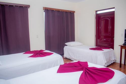 ein Zimmer mit zwei Betten mit roten Bögen darauf in der Unterkunft Hotel Santos Pina in São Filipe