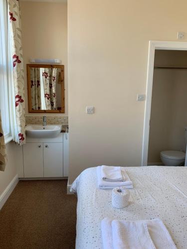 y baño con cama, lavabo y espejo. en Kings Lodge Hotel en Great Yarmouth