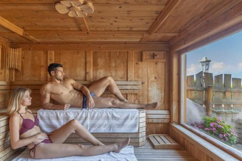 a man and a woman sitting in a sauna at Miraval Hotel in Coredo