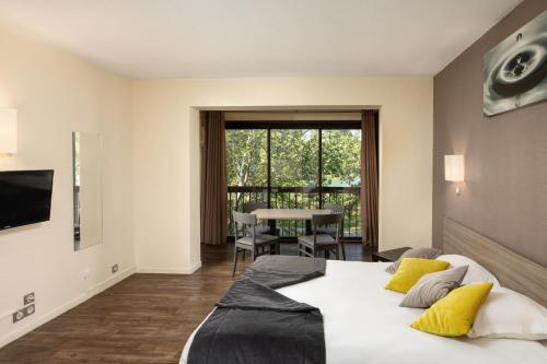 a bedroom with a large bed with yellow pillows at SOWELL Family Les Amandiers in Arles