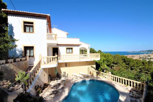 a villa with a swimming pool in front of a house at Holiday Home Impala in Jávea