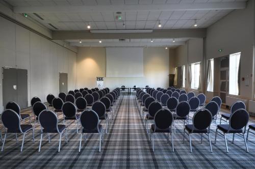 an empty room with chairs and a white screen at Mercure Orléans Portes de Sologne in Ardon