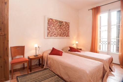 a bedroom with two beds and a chair and a window at Gaudi Apartment 9 in Barcelona