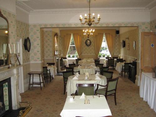 a dining room with tables and chairs and a chandelier at Ebury Hotel Cottages and Apartment's in Canterbury