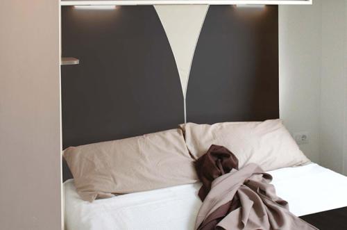 a bed with a black and white headboard and pillows at Villaggio Camping Adria in Casal Borsetti