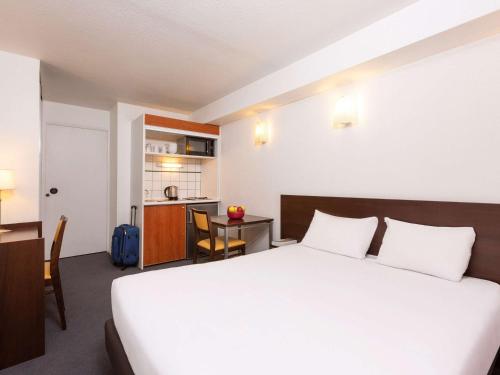 a hotel room with a large bed and a kitchen at Aparthotel Adagio Access La Défense - Léonard De Vinci in Courbevoie