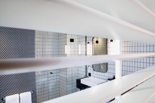 a white bathroom with a sink and a mirror at Maison ELLE Paris in Paris