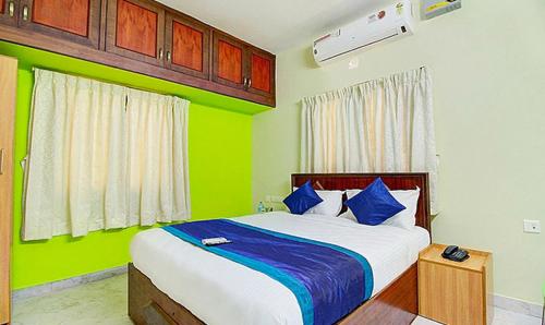 a bedroom with a bed with blue and green walls at FabExpress Apple Grand Gandhipuram in Coimbatore