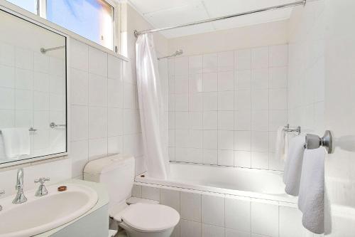 baño blanco con bañera, aseo y lavamanos en Econo Lodge Griffith Motor Inn, en Griffith