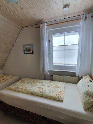 two beds in a small room with a window at Eden´s Ferienwohnungen in Neuharlingersiel