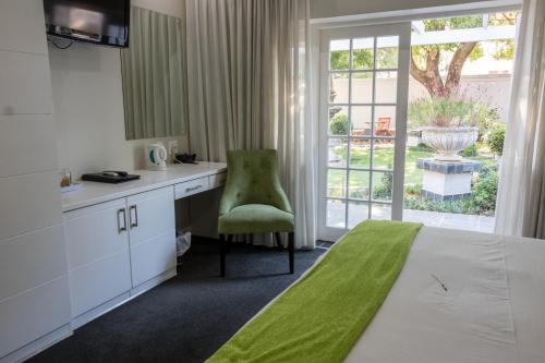 um quarto com uma cama, uma secretária e uma cadeira em Touch of Class Guest House em Pretoria