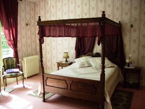 a bedroom with a canopy bed with red curtains at Chateau de la Garenne in Guînes