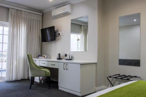 um quarto com um lavatório, um espelho e uma cama em Touch of Class Guest House em Pretoria