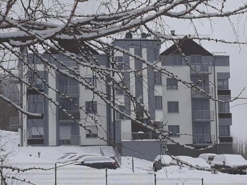 a large white building with snow on the ground at Apartament Szary Wilk in Świeradów-Zdrój