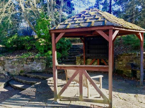 a wooden gazebo with a chair in a garden at Drumdevan Country House, Inverness in Inverness