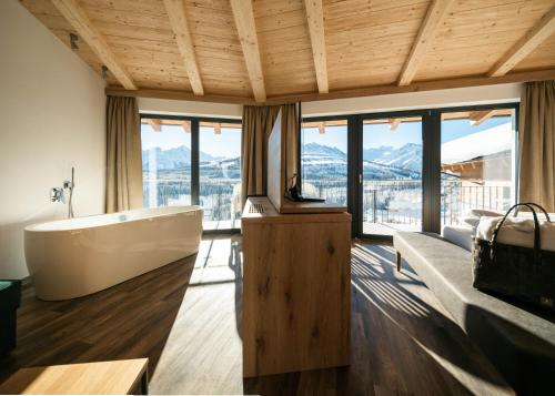 a bathroom with a tub and a large window at URSPRUNG Panorama Hotel Königsleiten in Königsleiten