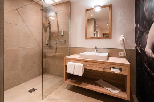 a bathroom with a tub, sink and mirror at Ursprungs Panorama Hotel Königsleiten in Königsleiten