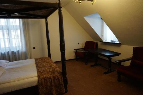 a bedroom with a four poster bed and a desk at Hotel Dwór Polski in Wrocław