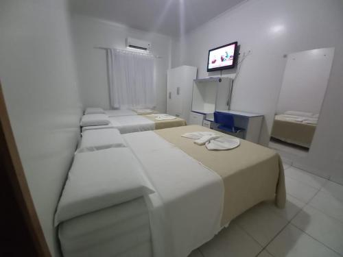 um quarto branco com três camas e uma televisão em Hamara Soft Hotel 1 em Altamira