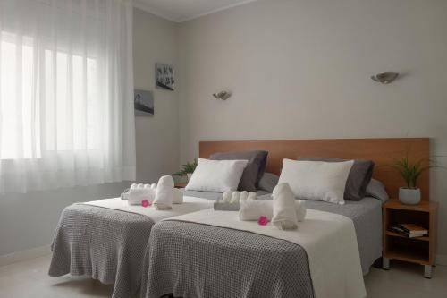 2 Betten mit weißer Bettwäsche und rosa Blumen drauf in der Unterkunft Hotel Tolosa in Salou
