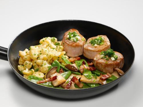 a plate of food with meat and vegetables in a pan at Landzeit Motor-Hotel Mondsee in Mondsee