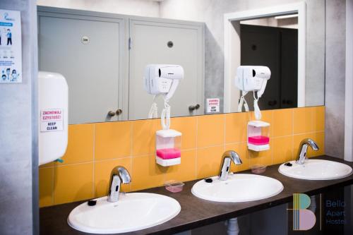 a public bathroom with two sinks with soap dispensers at Kapsuły Bello ApartHostel in Warsaw
