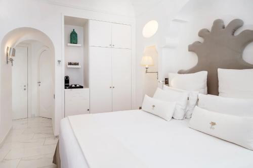 a white bedroom with a large white bed with white pillows at Hotel Villa Franca in Positano