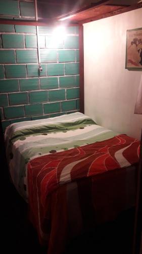 Habitación pequeña con cama y pared de ladrillo en Viajeros en Salta