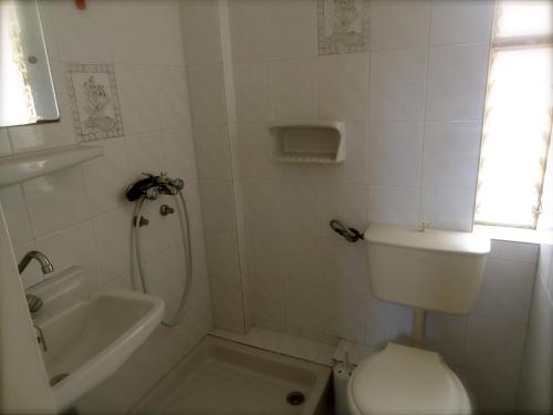 a white bathroom with a toilet and a sink at Eleni's Rooms in Loutra Edipsou