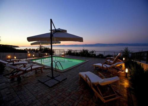 a swimming pool with chairs and an umbrella at Apartments Grlica in Sutivan