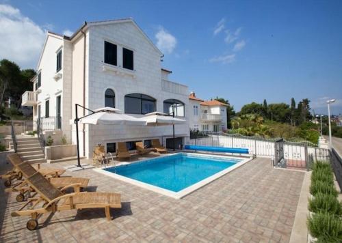una casa con piscina di fronte a una casa di Apartments Grlica a Sutivan (San Giovanni di Brazza)