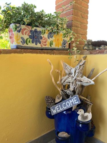 a blue pot with a welcome sign next to a plant at La Nana Gialla in Riotorto